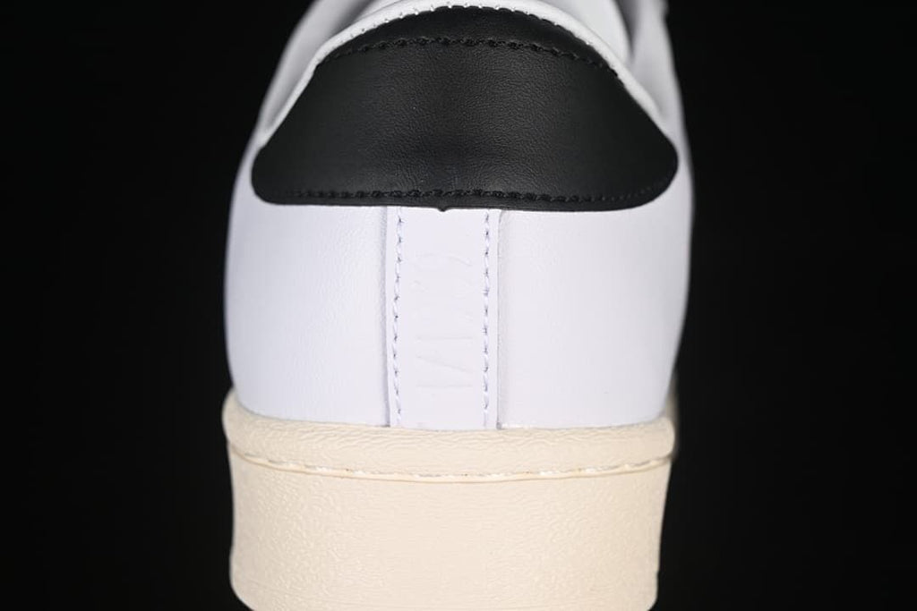 Rear view of the white sneaker with a black heel tab and cream outsole