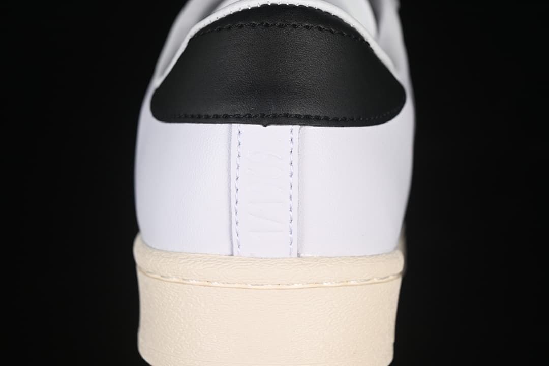 Rear view of the white sneaker with a black heel tab and cream outsole