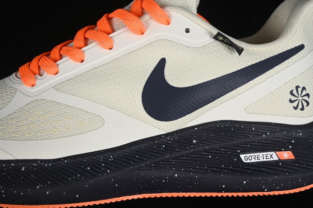 Close-up of the shoe side with navy swoosh, bright orange laces, and GORE-TEX badge