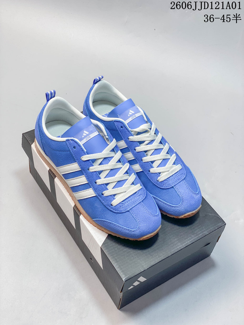 Pair of blue adidas VS JOG 2.0 low-top sneakers with white stripes and gum-colored outsoles