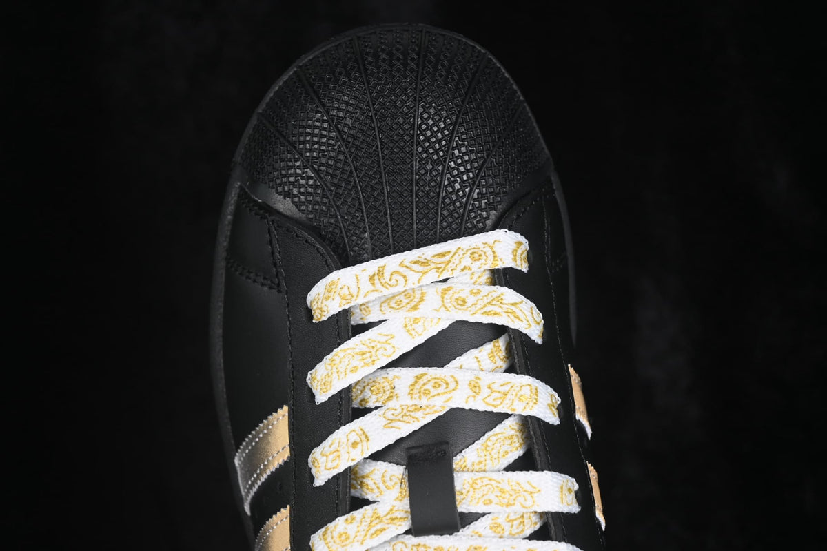 Close-up of the patterned white-and-gold laces and black textured shell toe.