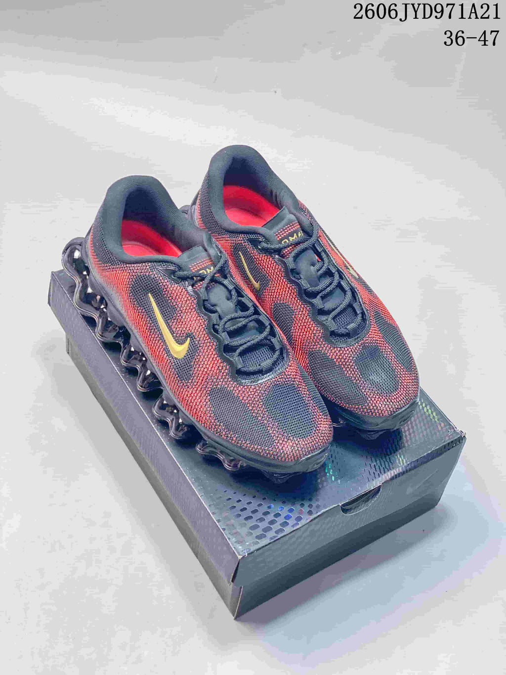 Pair of patterned navy, red and gold Nike Air Liquid Max shoes shown from above on a box; image also displays a size range.