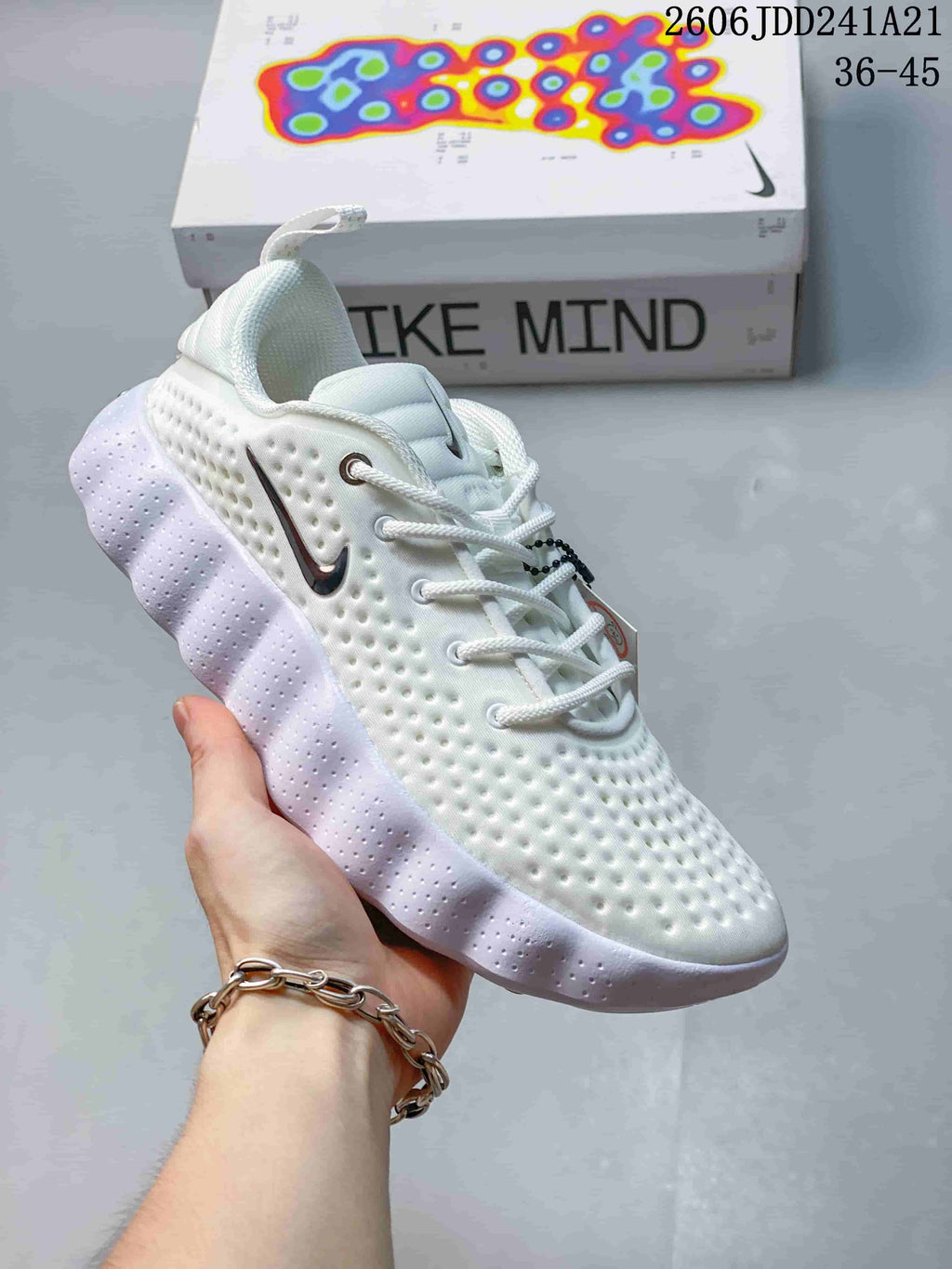 Angled side view of a white Nike Mind shoe with a sculpted pale lavender outsole