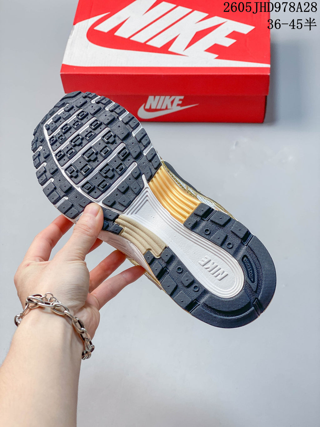 Underside view of the Nike Initiator outsole with dark tread and white and gold-tone sections