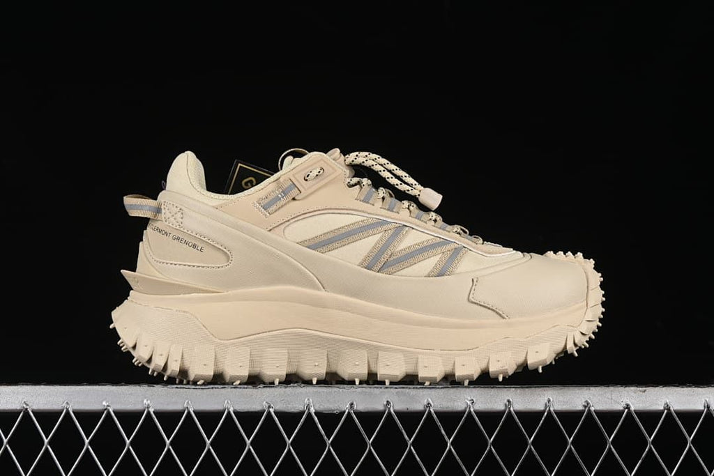 Side profile of a beige sneaker with striped panels and a rugged sole.