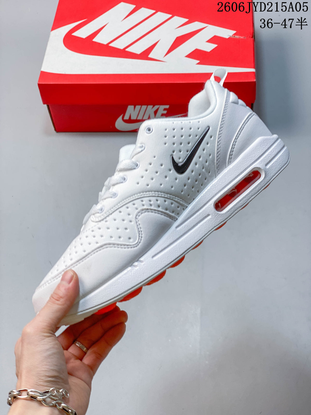 Side view of the white sneaker with perforated panels, dark Swoosh, and orange midsole window