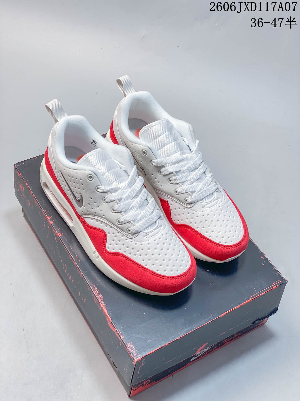 Pair of white and red Nike Air Max 1 sneakers shown from the front and side