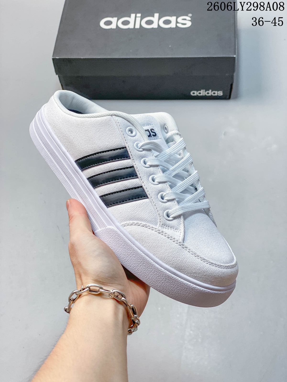 Close-up of a white adidas mule sneaker with dark side stripes and a lace-up front.