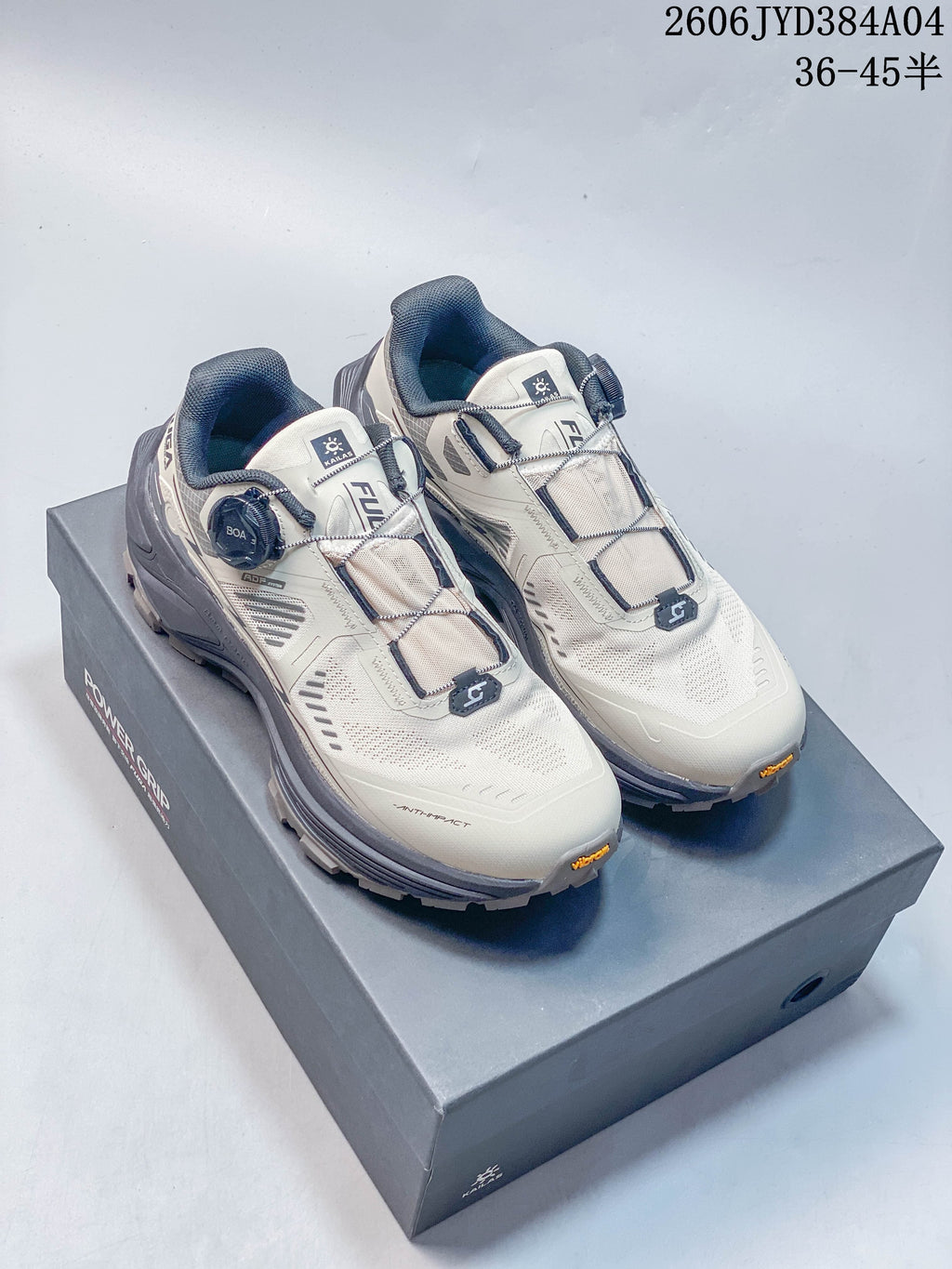 Pair of light-colored Kailas FUGA EX3 BOA trail shoes with dark gray accents, shown on a shoe box.