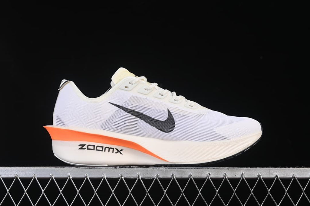 Side profile of the shoe showing the white upper, black Swoosh, and orange midsole accent