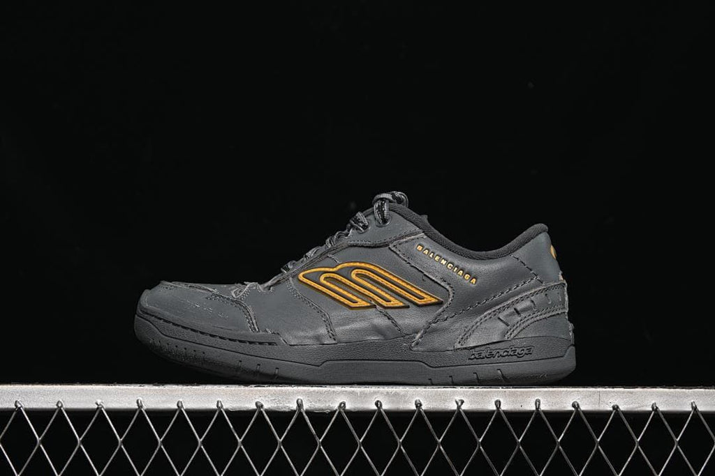 Side view of dark grey Balenciaga Hamptons sneakers with yellow-orange side emblem