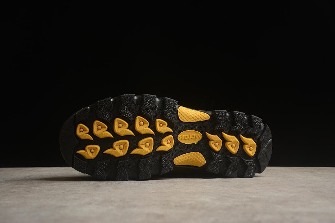 Underside view showing the black lugged outsole with yellow sections