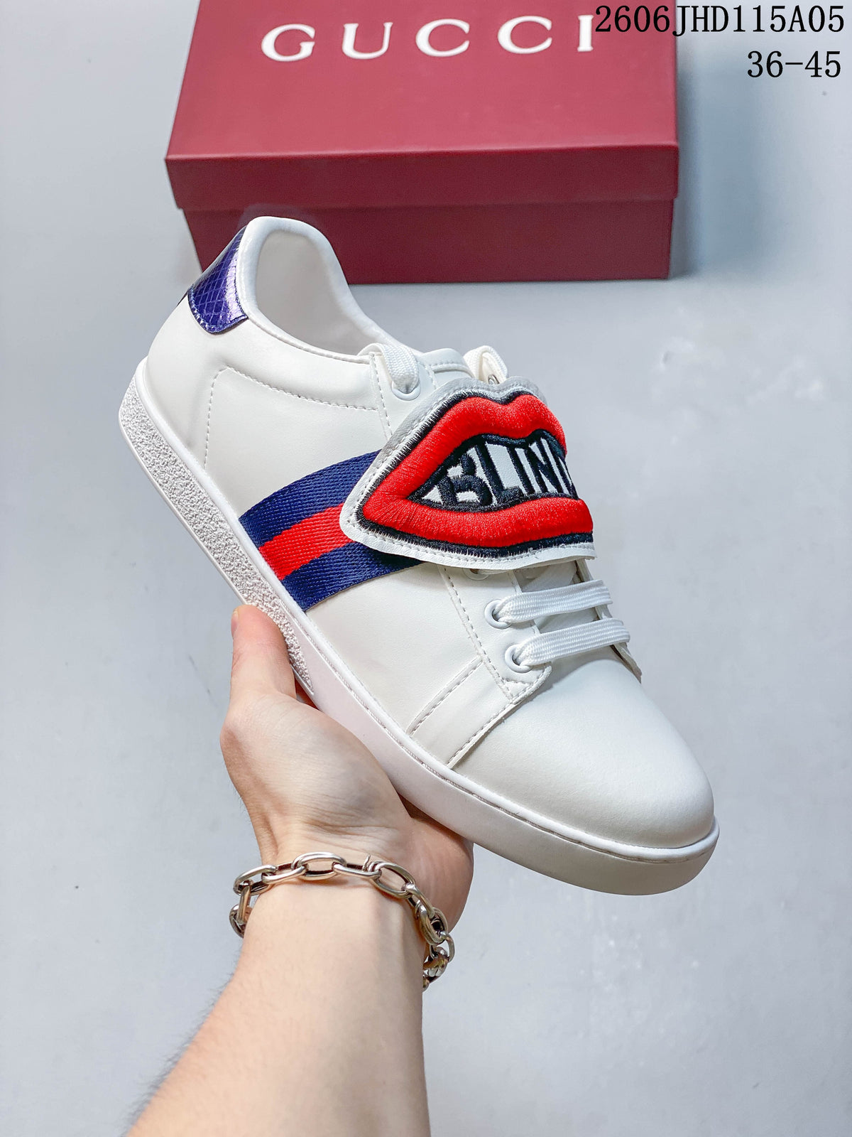 White low-top sneaker with a red embroidered lips motif on the tongue flap.