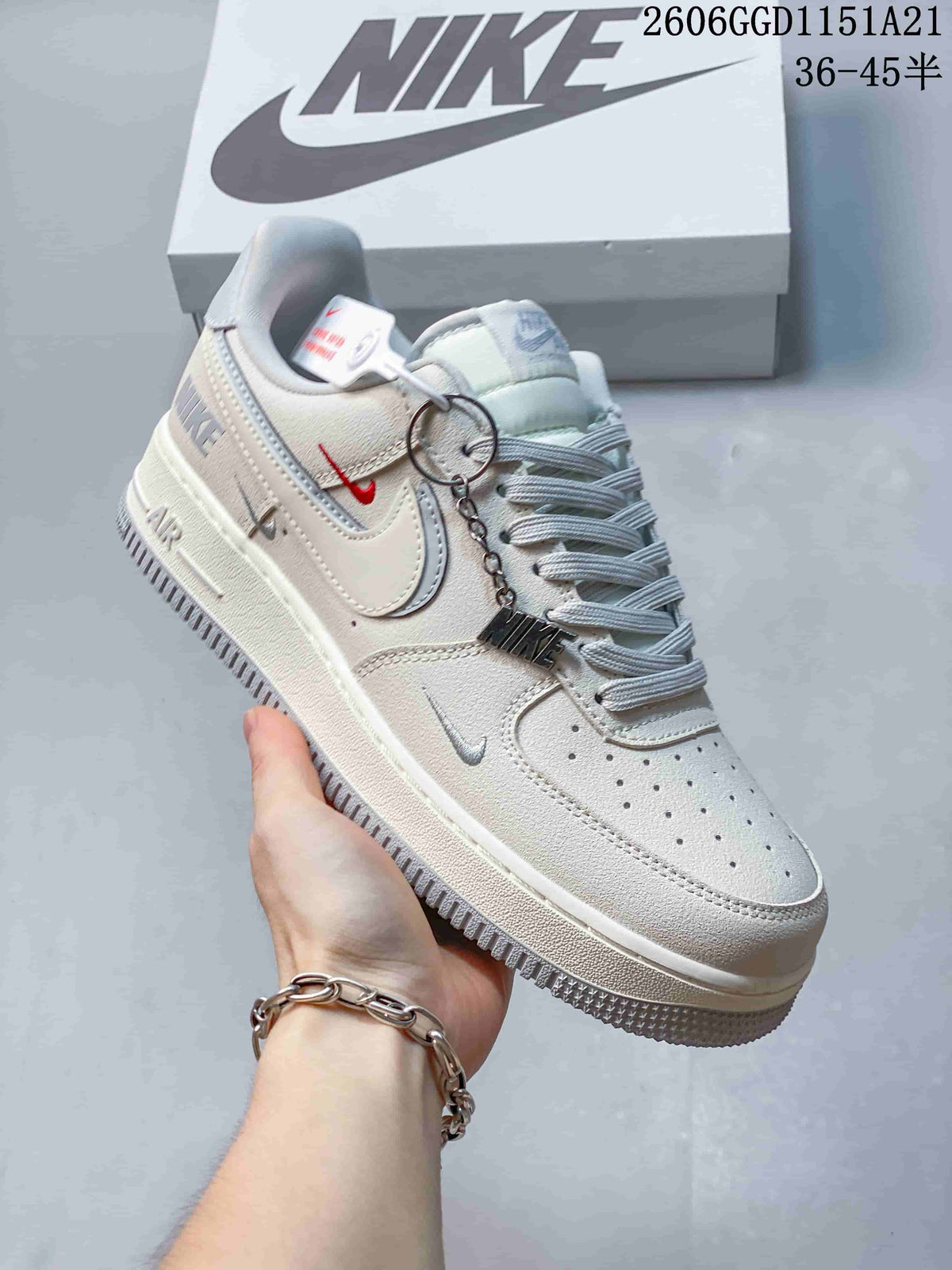 Angled view of a cream Nike Air Force 1 Low with pale blue accents and hanging charm
