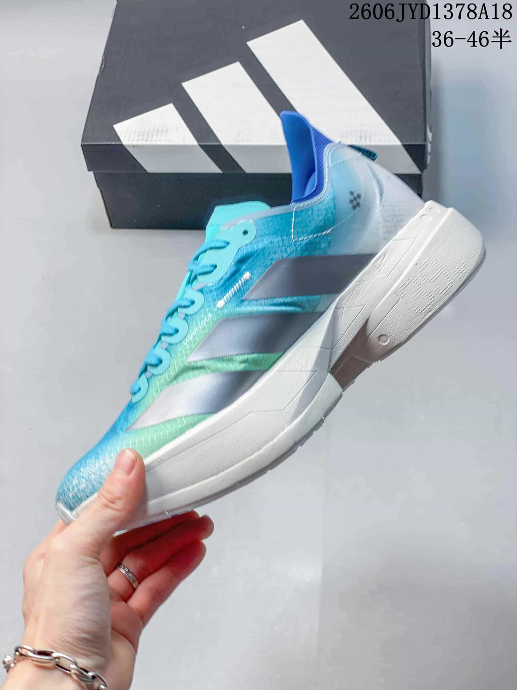 Side profile of a turquoise and blue running shoe with silver stripes and a white midsole