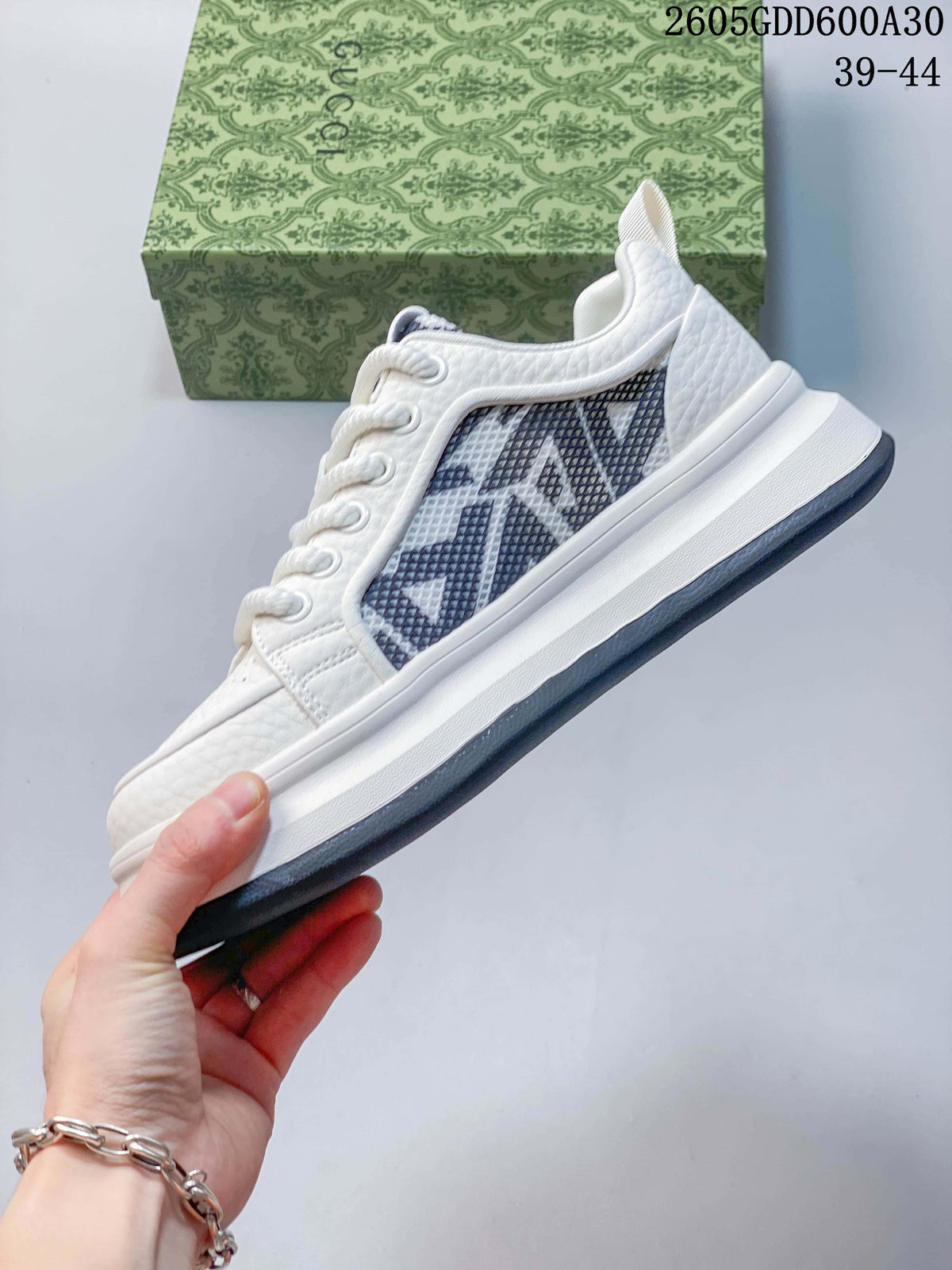 Side profile of the white sneaker with dark patterned inserts and a layered sole.