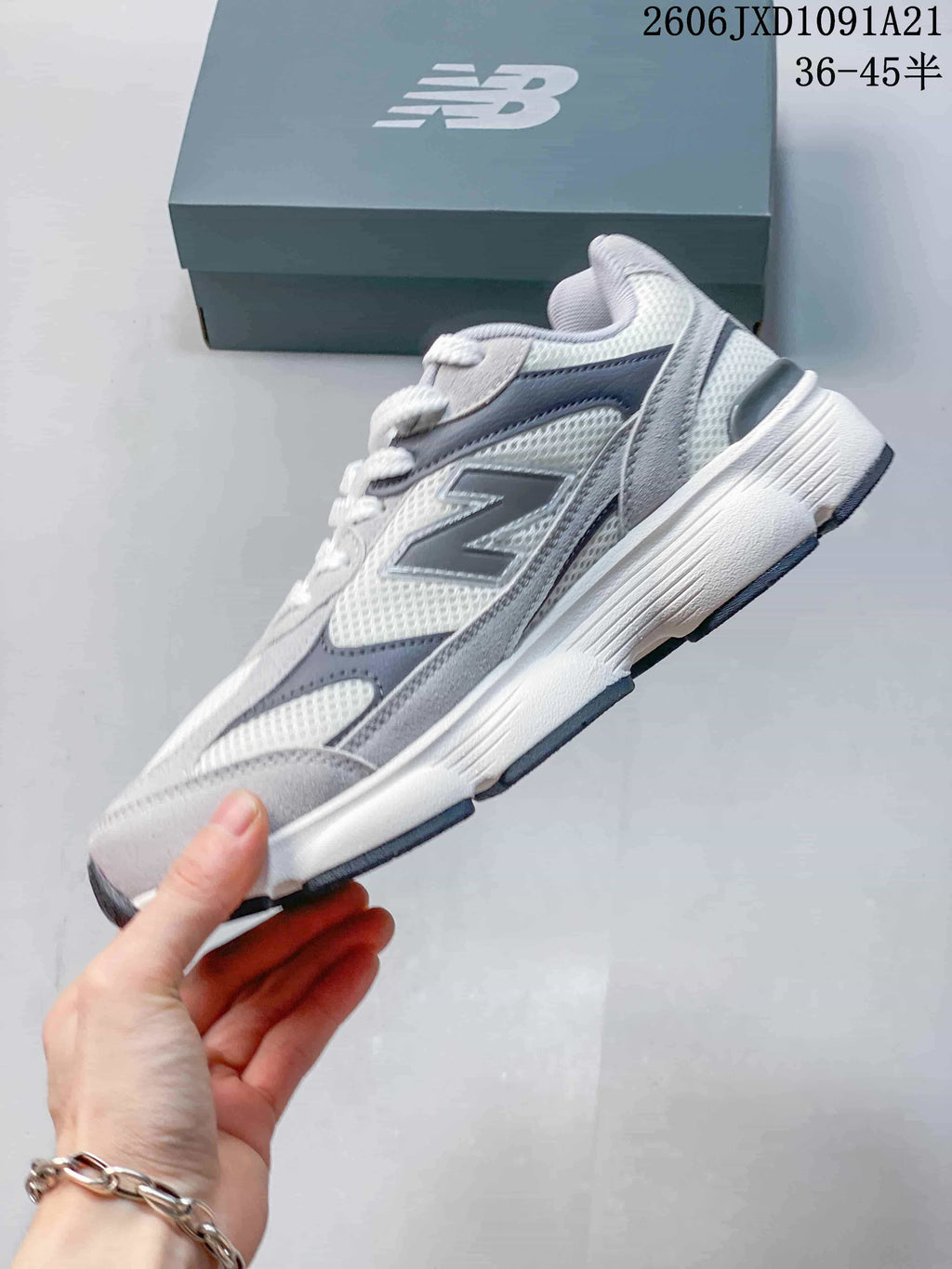 Side view of a gray and white New Balance sneaker with layered panels