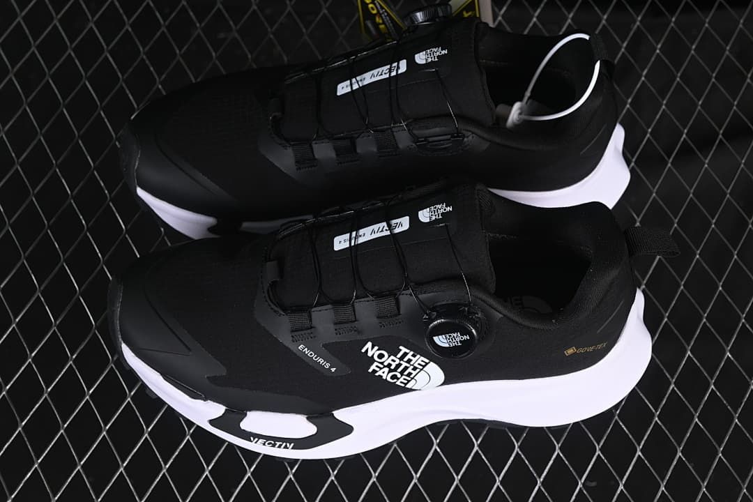 Pair of black low-cut shoes with white midsoles, shown from above.