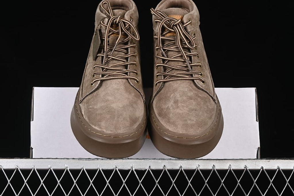 Front view of the pair of khaki lace-up boots resting on the box