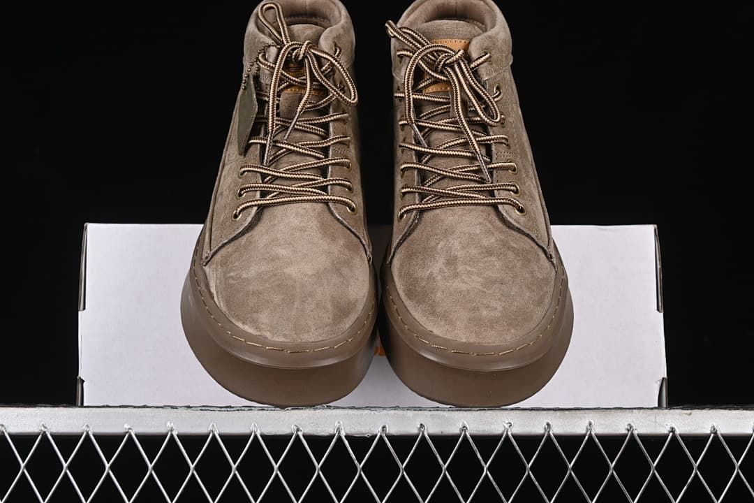 Front view of the pair of khaki lace-up boots resting on the box