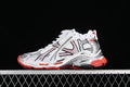 Side view of a white Balenciaga Runner-style sneaker with silver overlays, black detailing and red accents.
