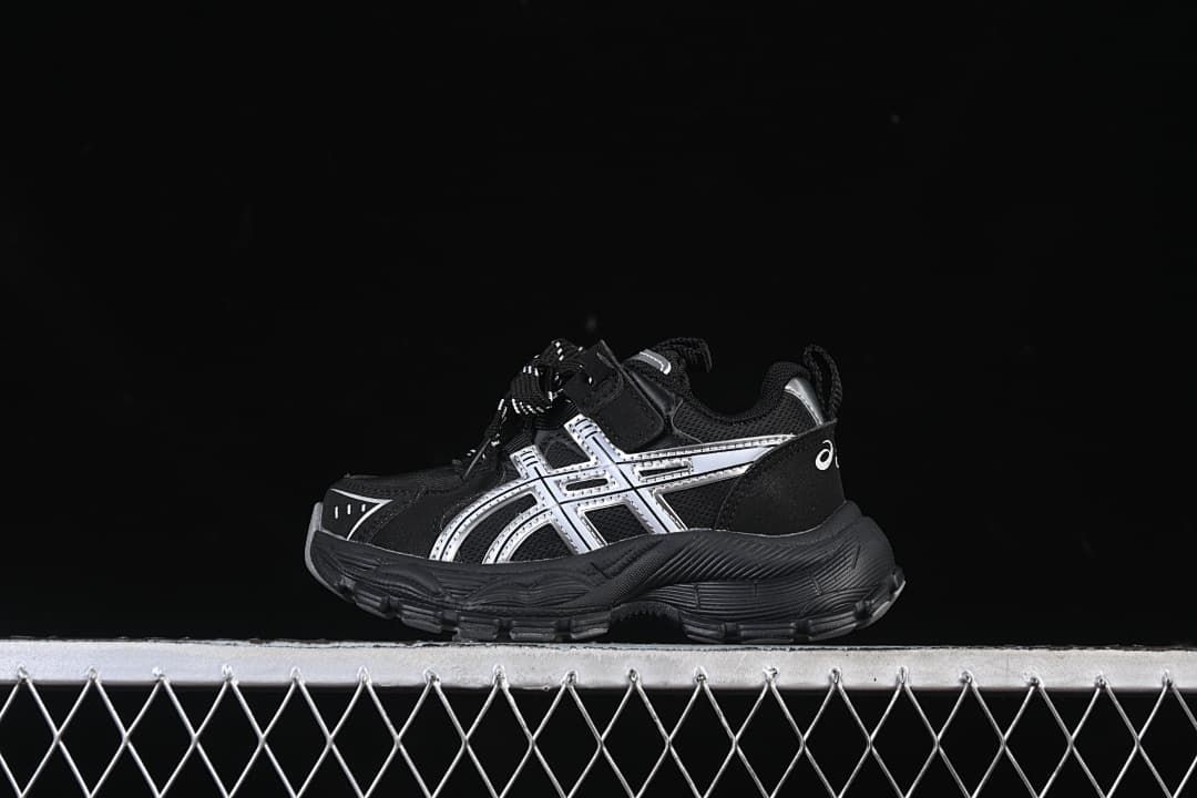 Black kids' ASICS sneaker with silver side details, shown in profile.