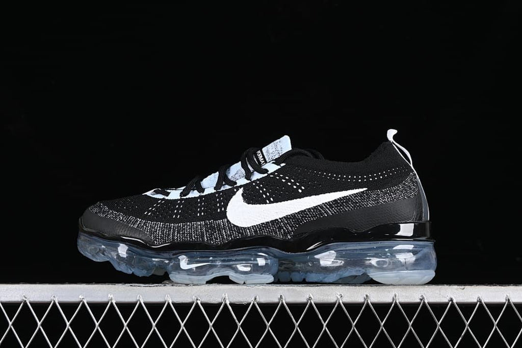 Side view of black and white VaporMax-style sneakers with a white Swoosh and translucent sole.