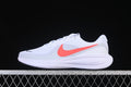 Side view of a white Nike Revolution 8 running shoe with a coral-colored Swoosh
