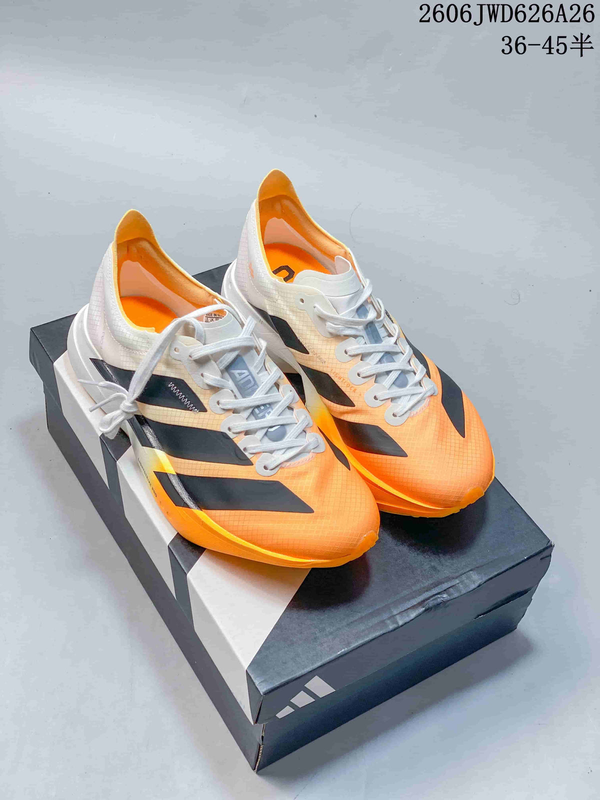 Pair of white, black, and orange Adidas Adizero Adios Pro 4 shoes on a box.