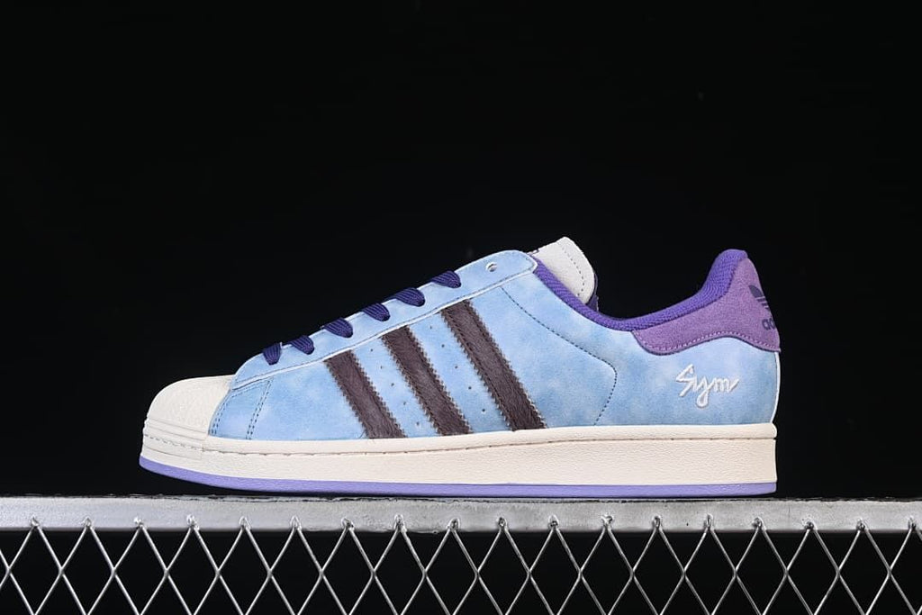 Side profile of a light blue adidas Superstar II sneaker with dark stripes, purple accents and an off-white shell toe