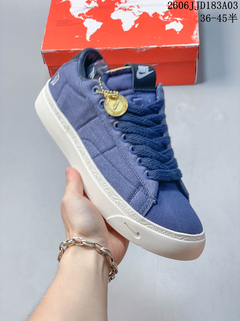 Blue low-top lace-up sneaker with a white decorated midsole and gold-tone charm