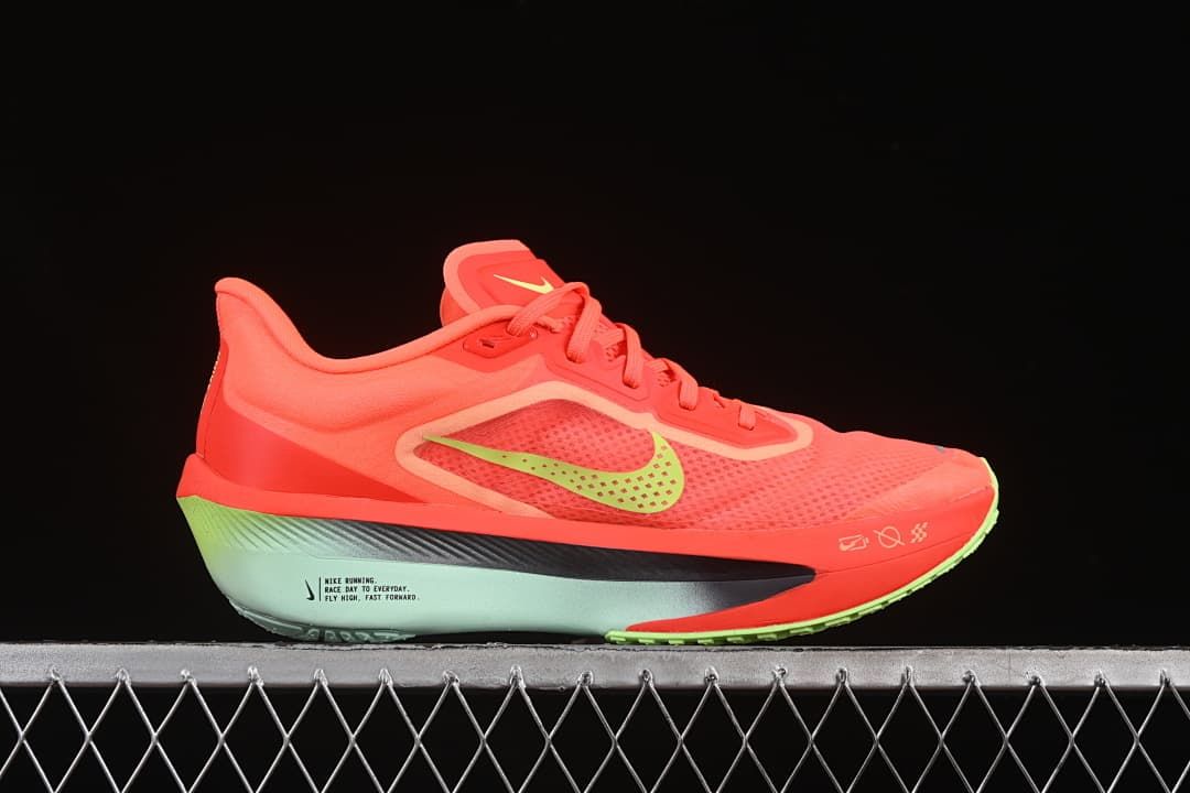 Side profile of coral running shoe with lime Swoosh and pale blue-green midsole