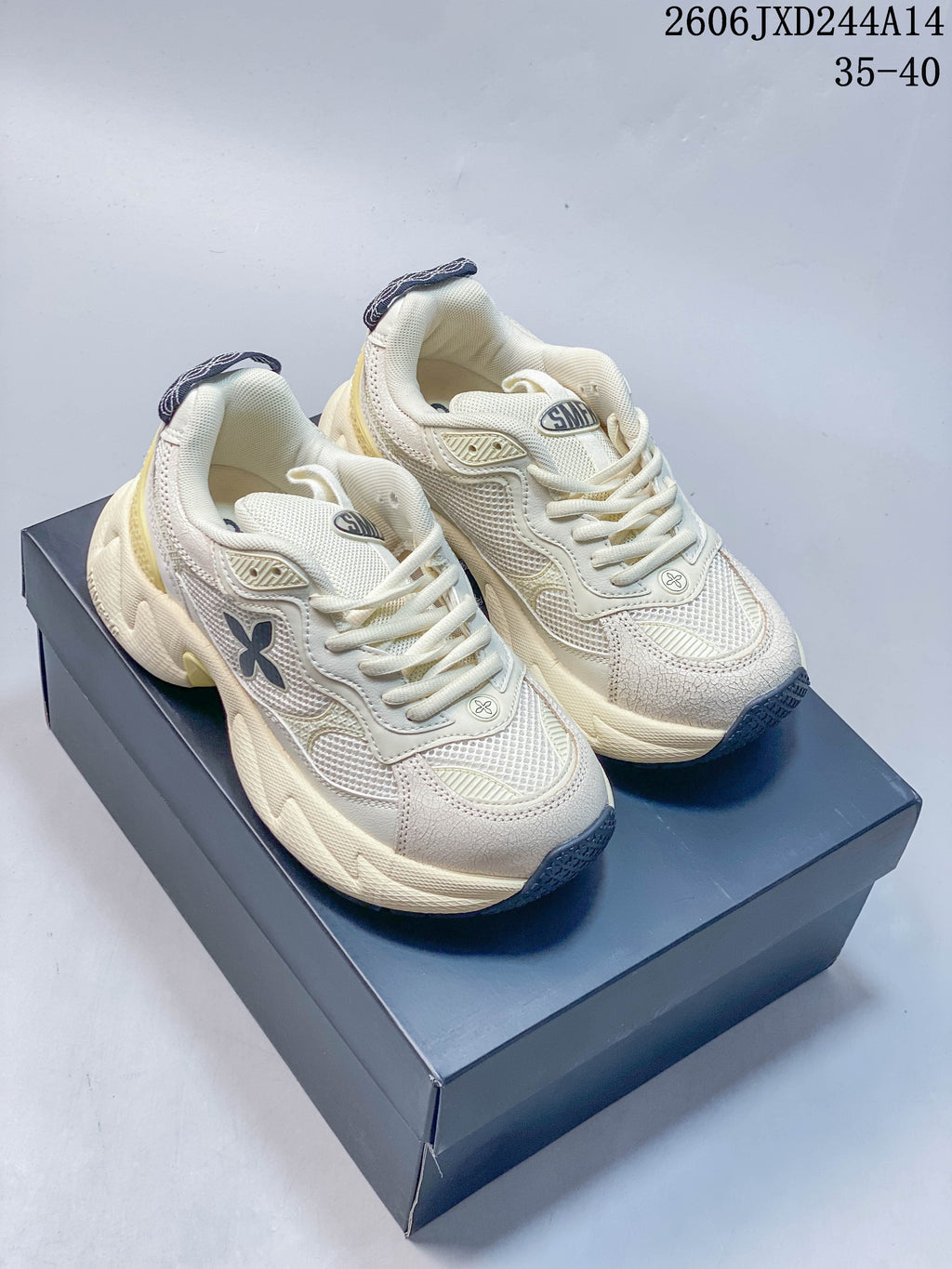 Pair of ivory-toned SMFK Future Ripple low-top sneakers with black accents and pale yellow details, shown from above.