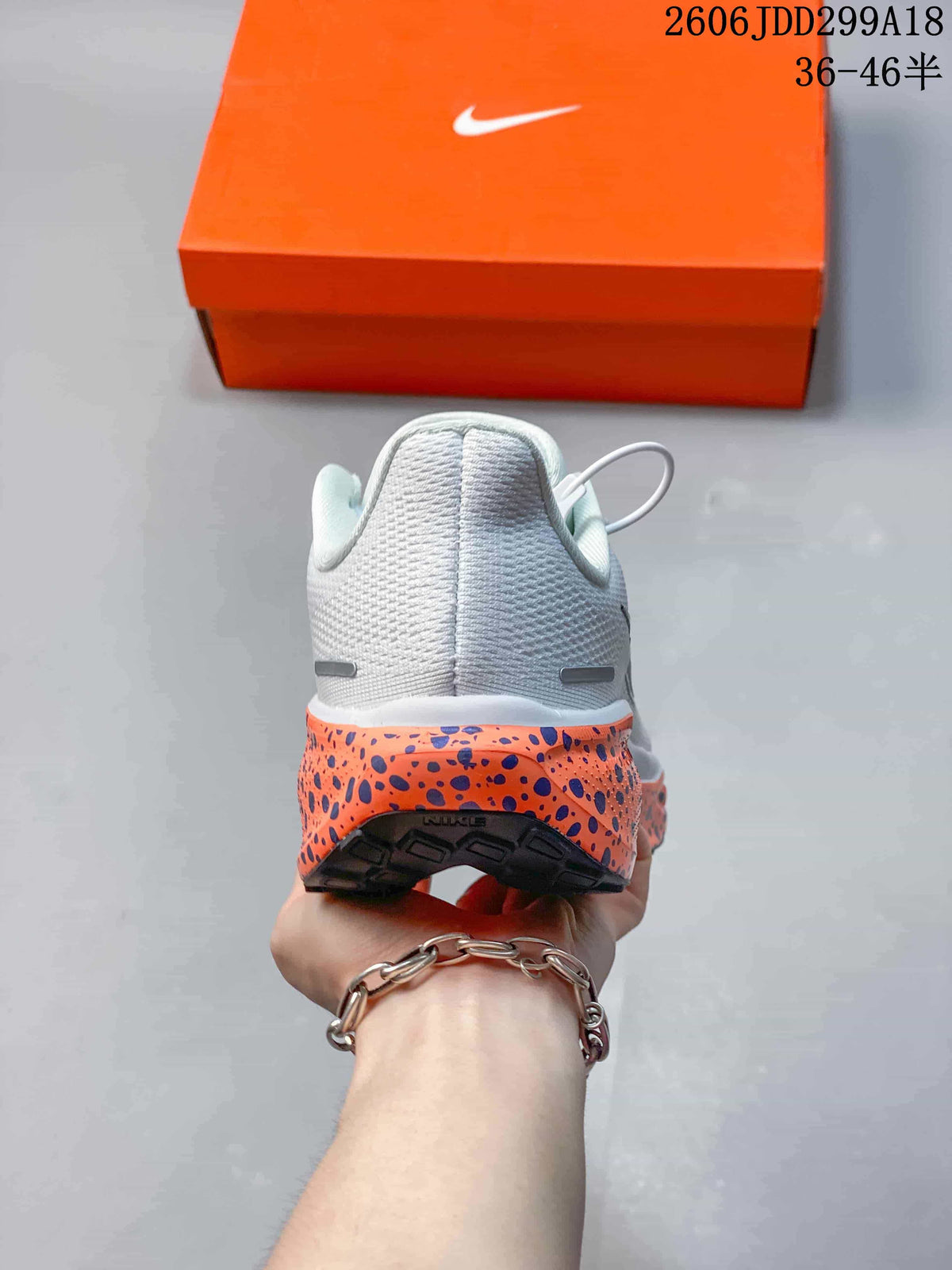 Rear view of a white Nike running shoe with an orange speckled midsole.