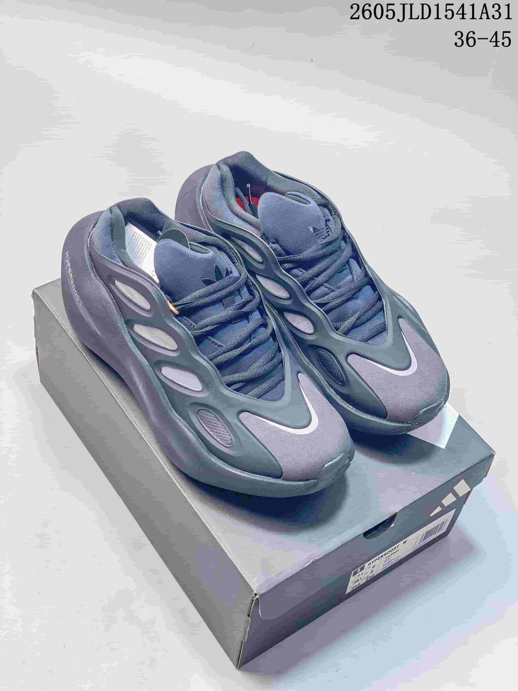 Pair of grey and navy Adidas Hyperboost sneakers displayed on a shoebox.