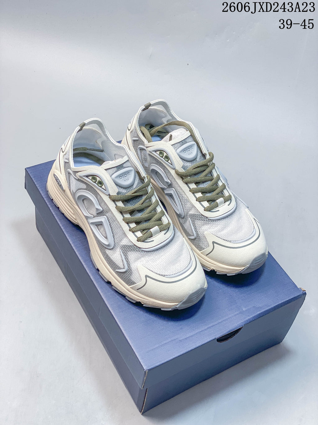Pair of gray and light-colored Dior B30 low-top sneakers with olive-toned laces, shown on a blue box