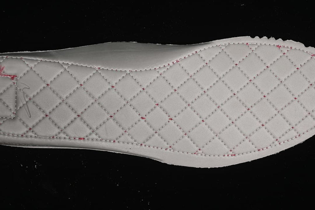 Close-up of a light-colored quilted insole with contrasting stitching.