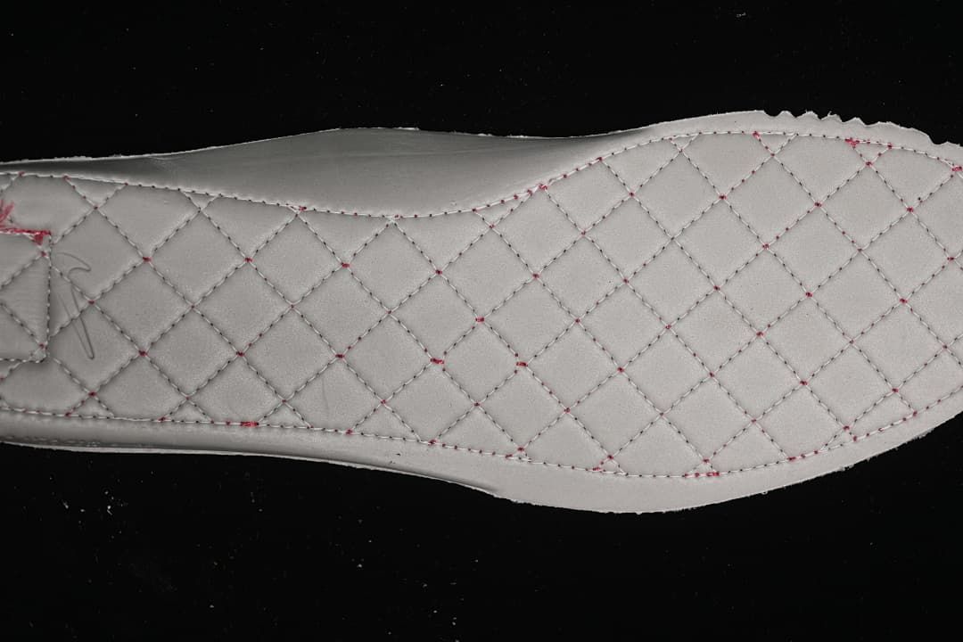 Close-up of a light-colored quilted insole with contrasting stitching.