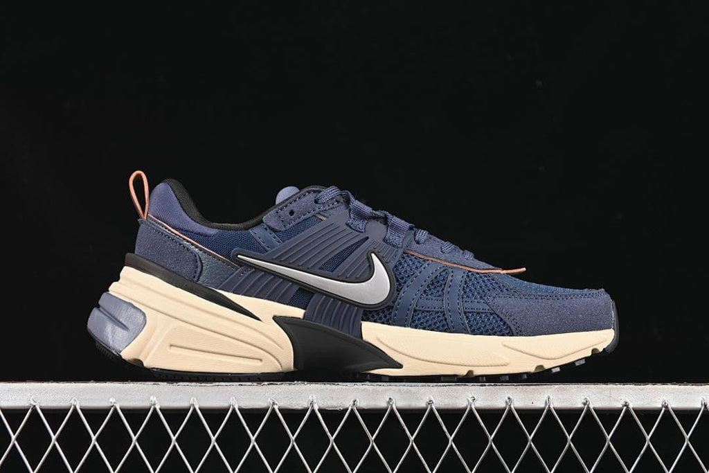 Side profile of the navy sneaker with cream-toned sole and peach-colored heel pull