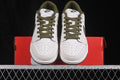 Front view of a pair of white and olive Nike low-top sneakers resting on a red shoebox.