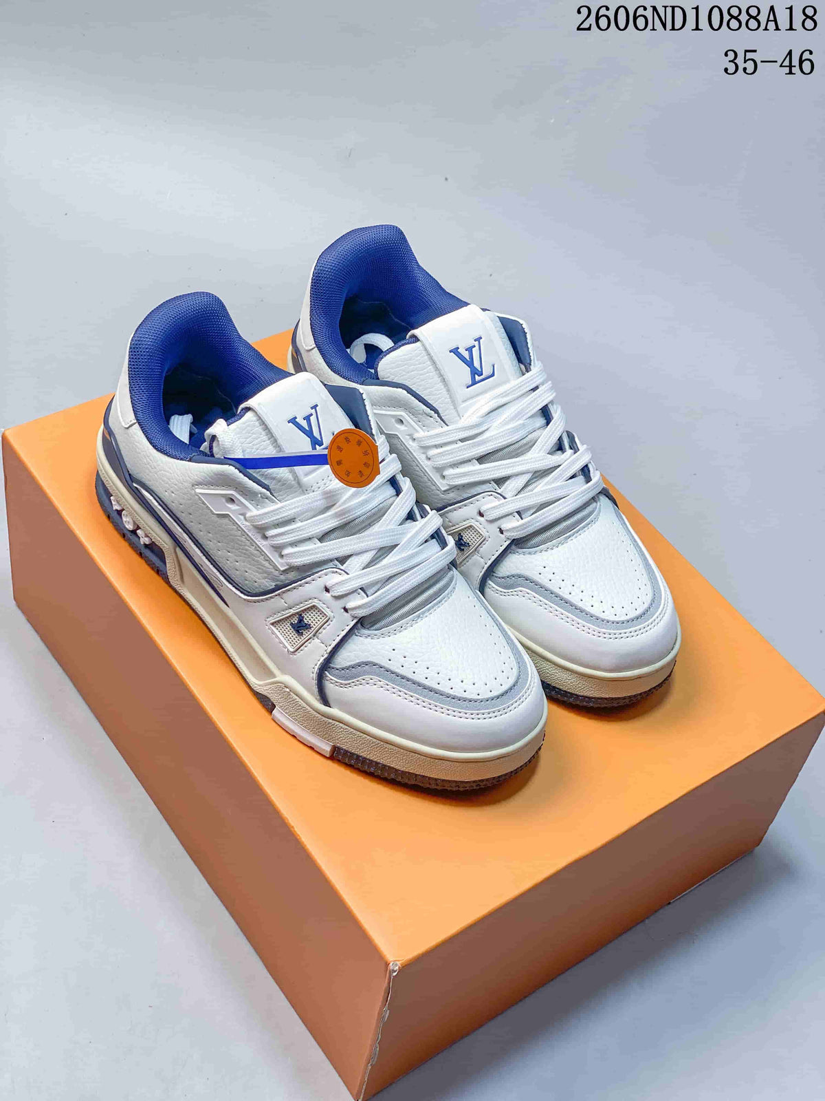 Pair of white and blue Louis Vuitton Trainer low-top sneakers on an orange box