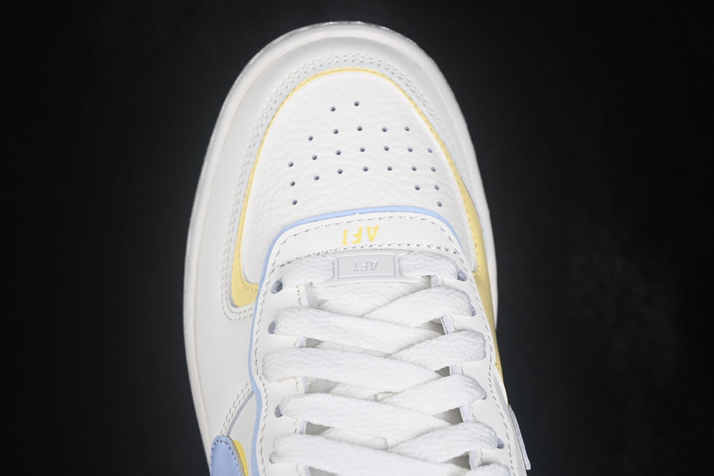 Top-down close-up of the perforated white toe box, layered trim, and white laces.