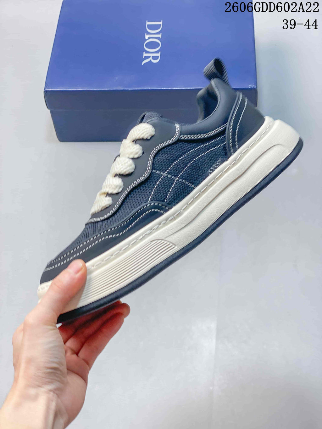 Side view of a navy low-top sneaker with contrast stitching and a layered off-white sole