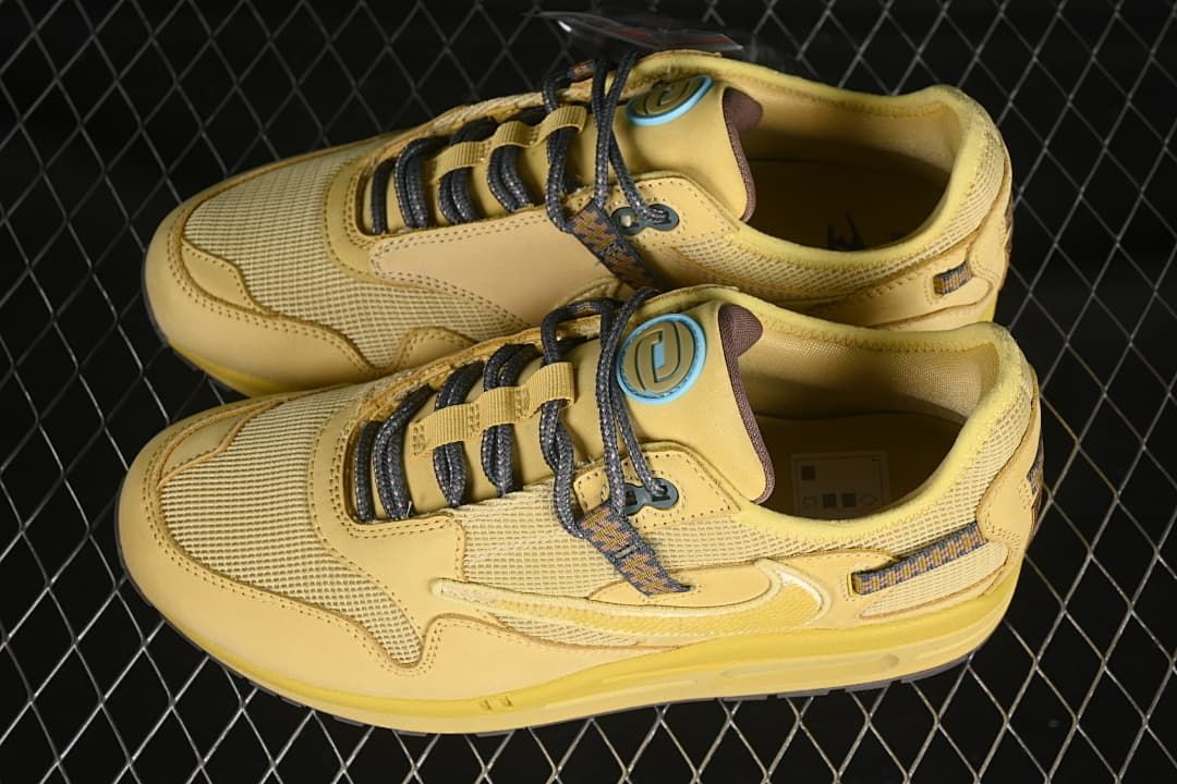 Pair of wheat-colored Nike Air Max 1 sneakers viewed from above.