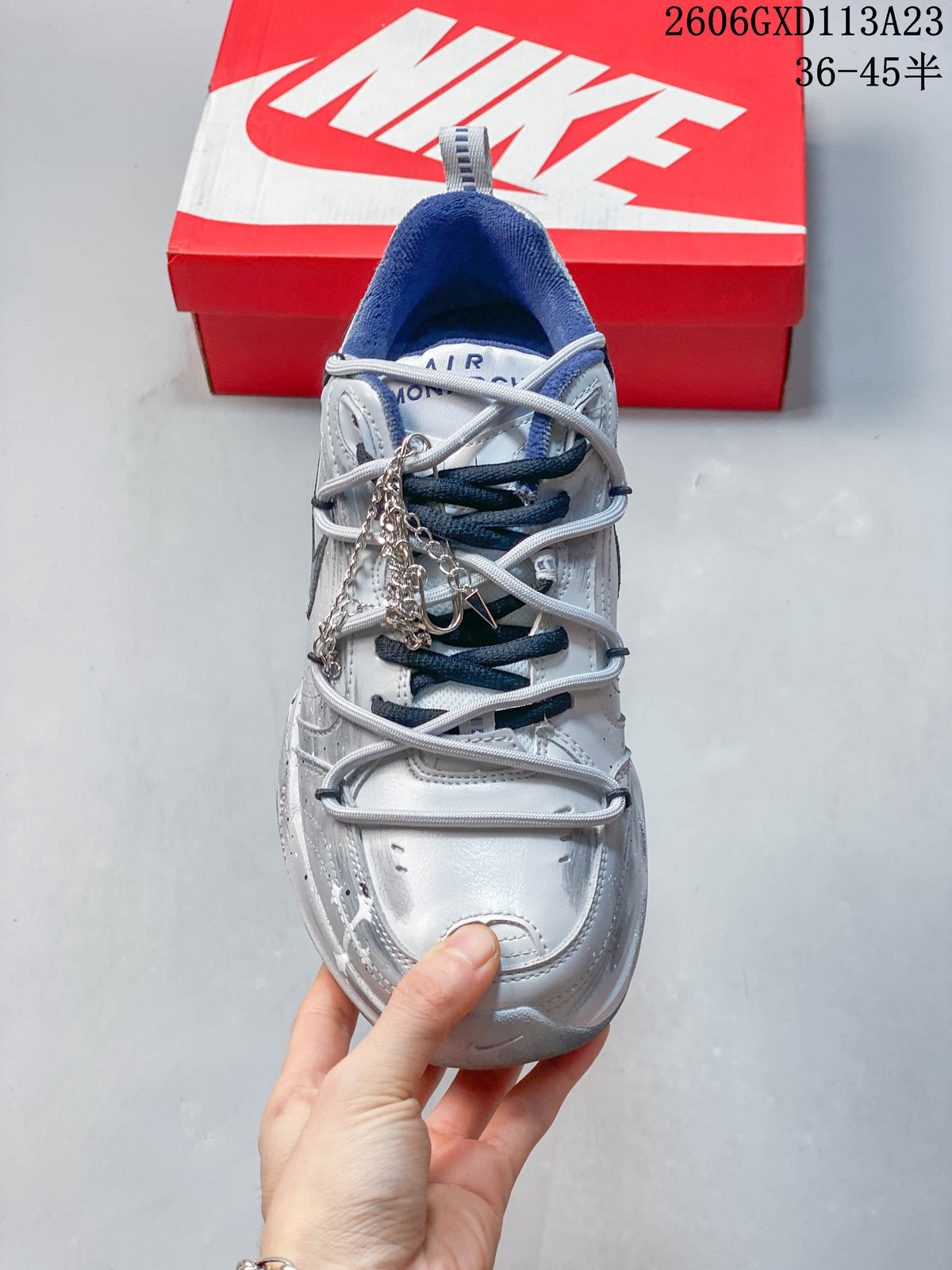 Top view of the sneaker showing its layered lacing, blue tongue and collar details, and decorative chain.