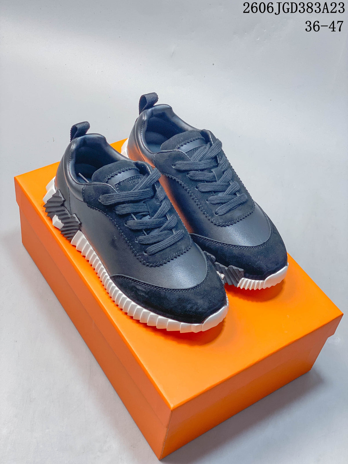 Pair of dark navy low-top sneakers displayed on an orange box.