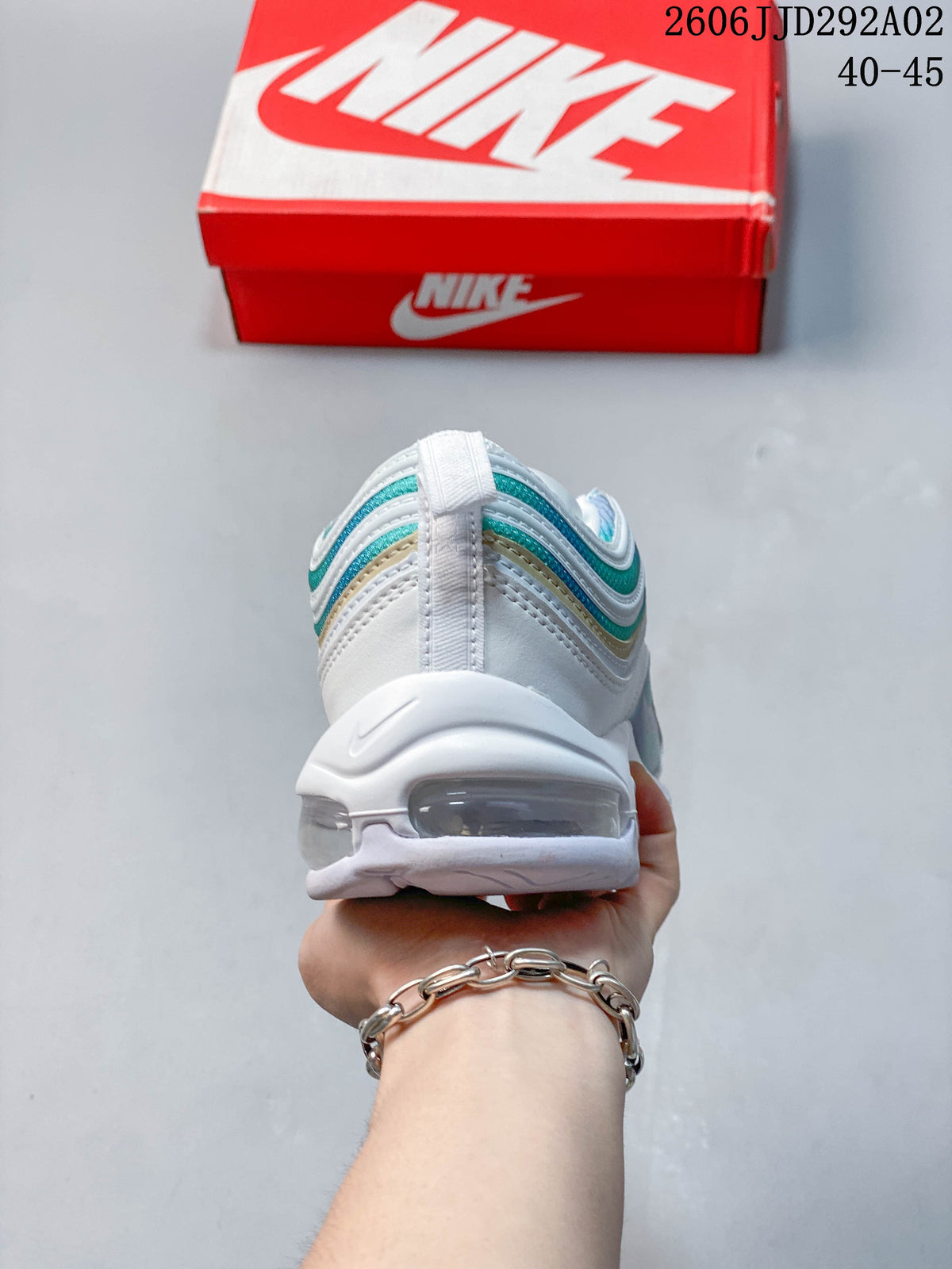 Rear view of a Nike Air Max 97 sneaker with layered aqua and white panels and a visible Air unit