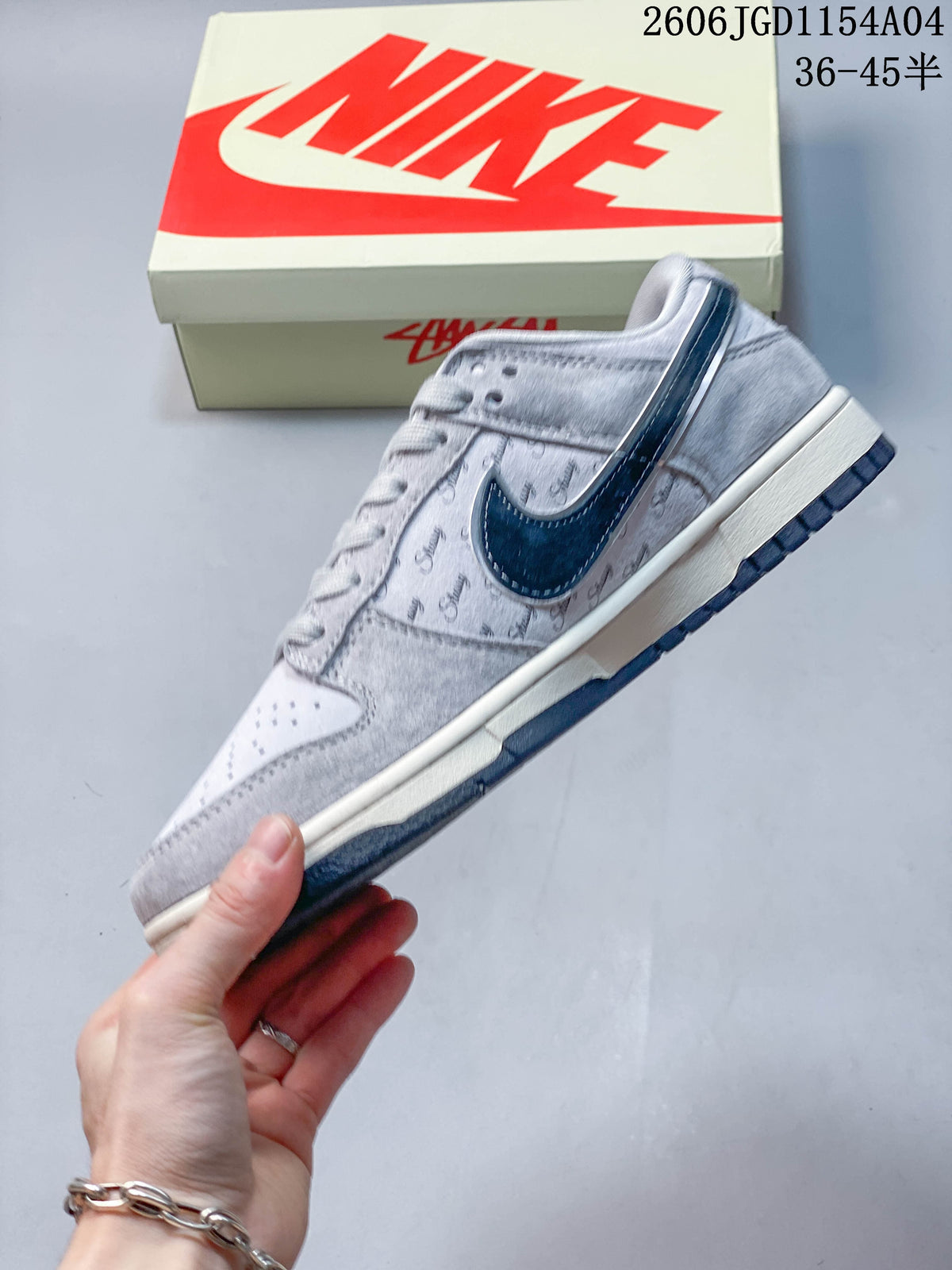 Side profile of a grey low-top sneaker with navy Swoosh and repeating Stussy script