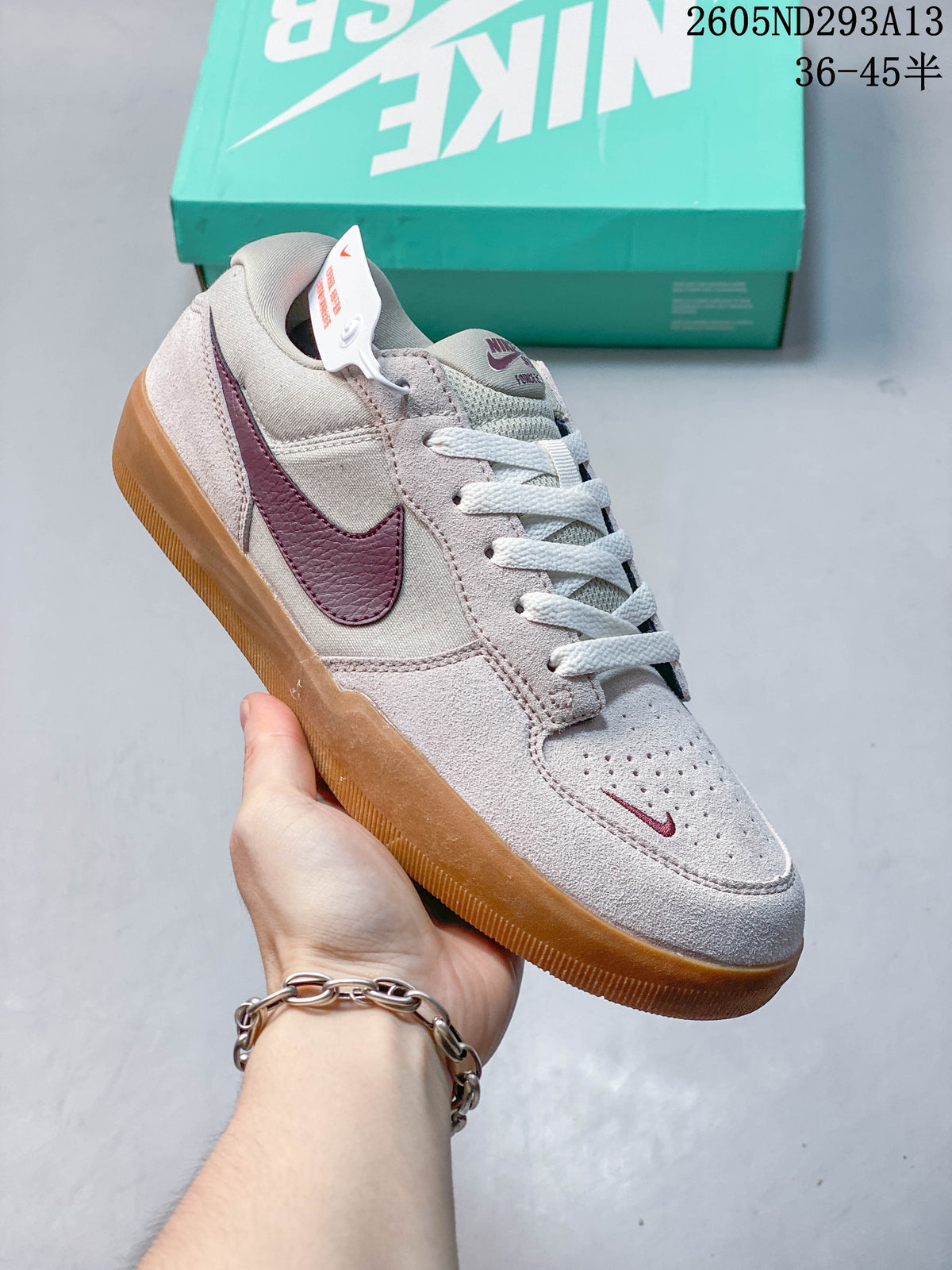 Angled close-up of a pale pink Nike SB Force 58 shoe with burgundy Swoosh and gum sole