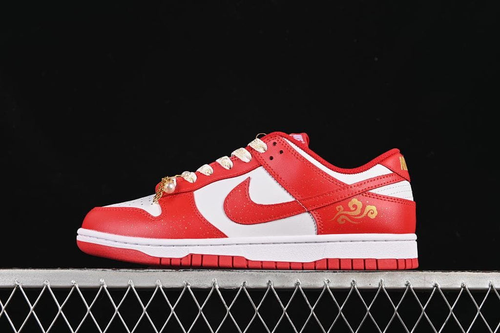 Side view of a red and white Nike Dunk Low with patterned laces and gold-tone accents